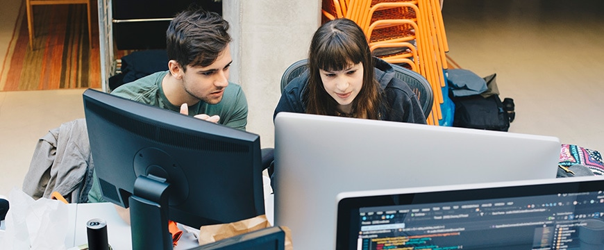 High angle view of computer programmers using desktop PC at office desk