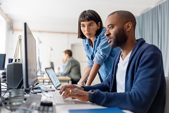 IT workers reviewing network data on computer screen.