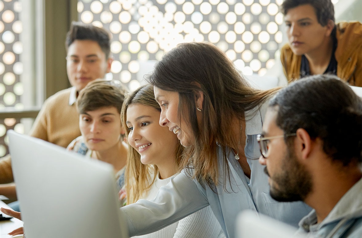 Teacher and students smiling and watching educational video on desktop computer the lesson in a classroom