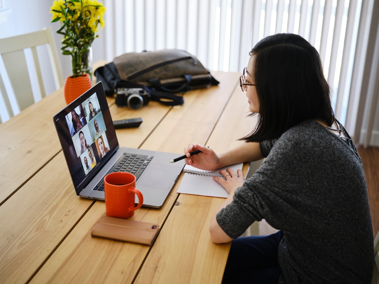 Person laughing while sitting on next to a laptop wearing headphones and attending a video call.