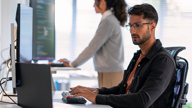 image of two IT specialists working on desktop computers in an office environment