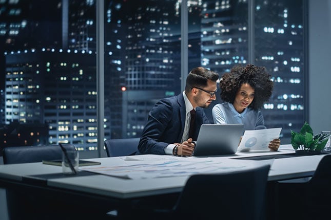 Businesspeople in Modern Office: Business Meeting of Two Managers. Accountant and Operations Director Talk, Discuss, Brainstorm Corporate Strategy, Implementing Budget and Financial Plans. Night.