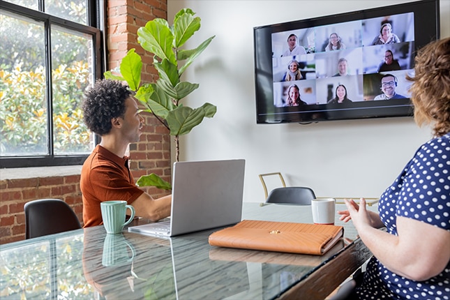 thumbnail image of two employees on a shared video conference call inside an office meeting room