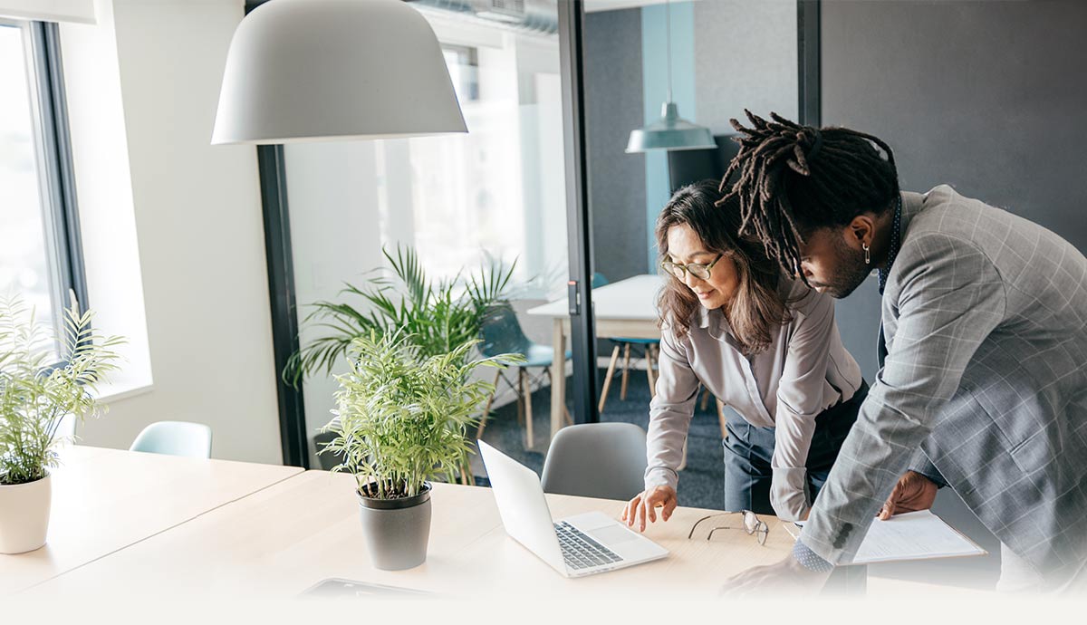 Two professionals collaborate at a laptop in a modern office setting with natural light, plants, and documents on the desk, visually supporting themes of AI-powered productivity, enterprise innovation, and Intel technology solutions delivered by CDW.