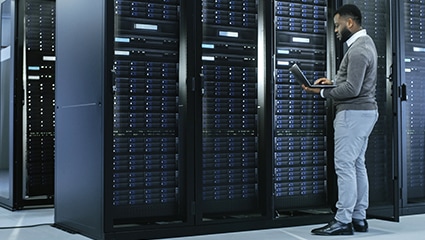 Person working on laptop in data center.