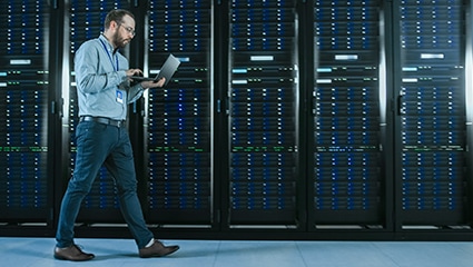 Person using laptop in brightly lit data center.