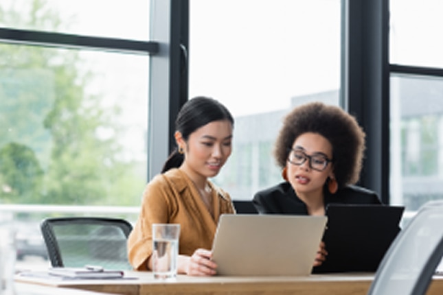 image of two women working on laptops in an office environment