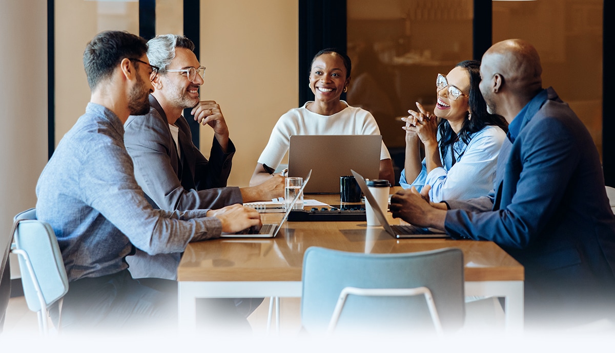 Employees talking during a meeting inside a bright office space.