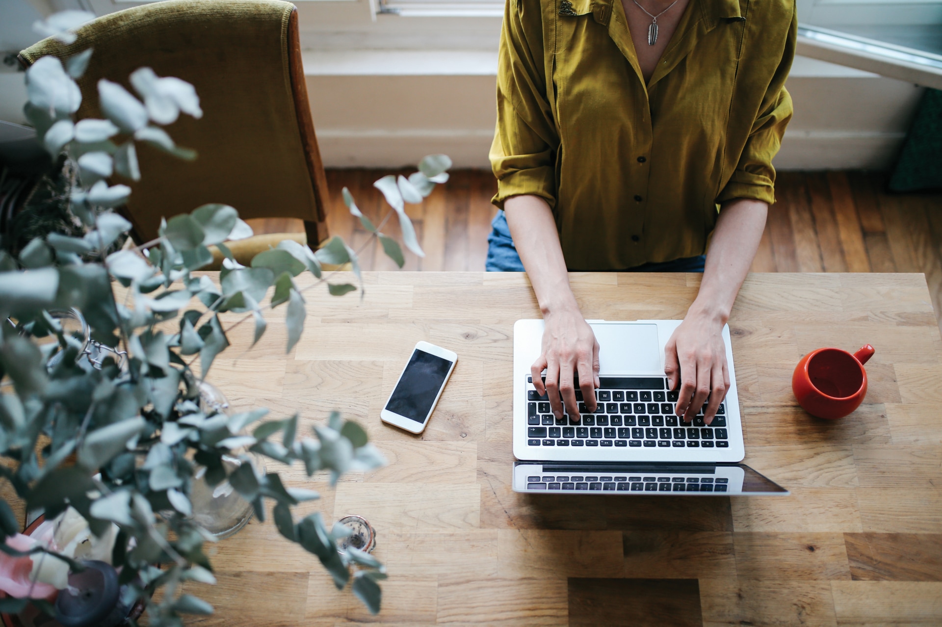 Image aérienne d’une romancière, blogueuse, pigiste ou photographe, tapant sur le clavier d’un ordinateur portable dans le salon de son appartement lumineux du centre-ville de Paris, dans le quartier de Montmartre. Elle dispose d’une belle table rétro en bois et un plancher en bois d’époque assorti. Rétro avec des couleurs vives. Blogueuse à la mode et indépendante, travaillant à partir du domicile dans une atmosphère décontractée et douillette à Paris, en France.