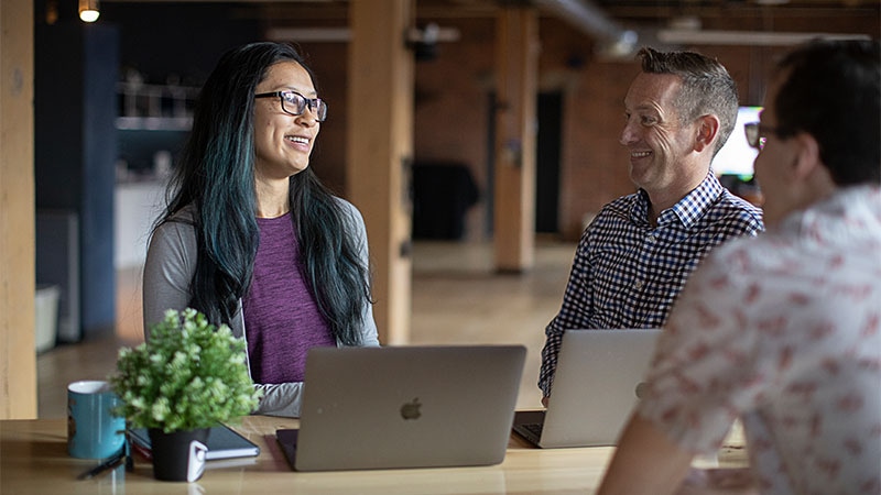 Team collaborating on Apple laptops in a modern office, representing secure and seamless Jamf integrations for managing and protecting organizational data.