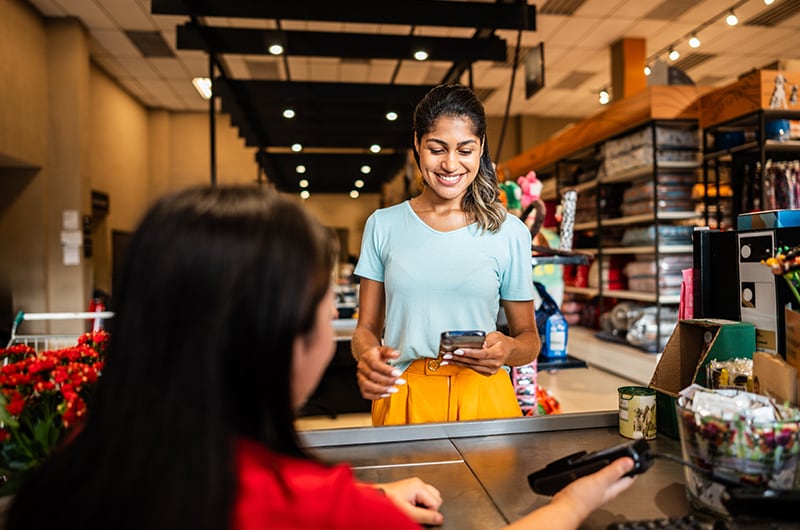 image of a woman paying with her smartphone during checkout at a retail store