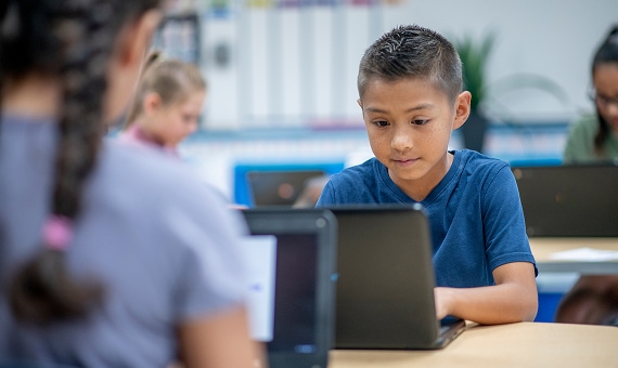 Student focused on a laptop during a classroom technology lesson.