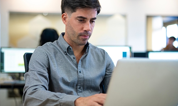 Professional working on a laptop in a modern office environment.