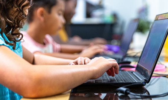 Students typing on laptops during a supervised classroom activity.