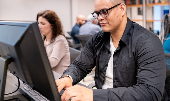 IT professional working at a desktop computer in an office setting.