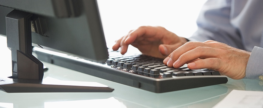 Closeup of a person using a keyboard in a bright office.