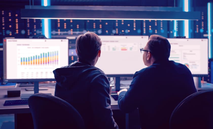 Two men looking at a desktop screen.