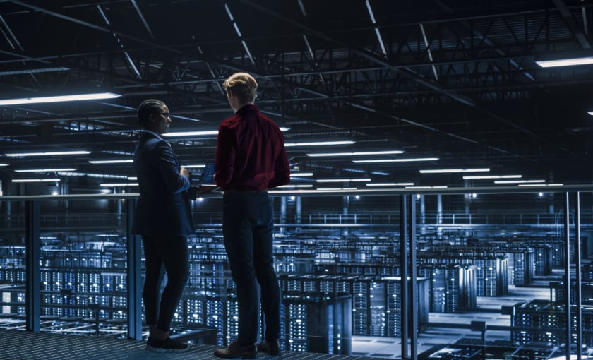 Two male IT technicians looking over a data center.