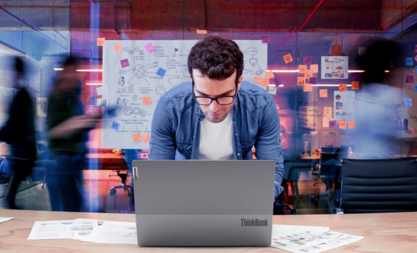 A man working on a laptop in a busy office.