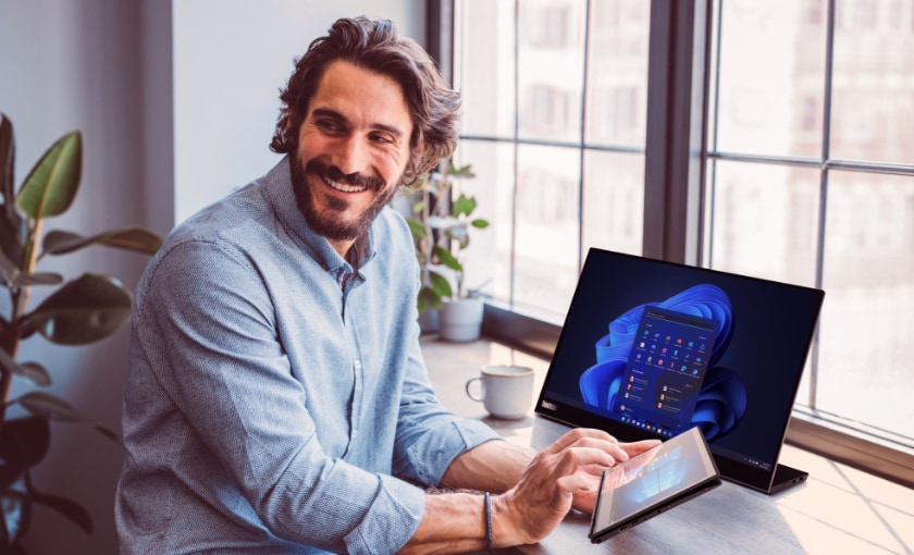 A smiling man working on his tablet at his desk.