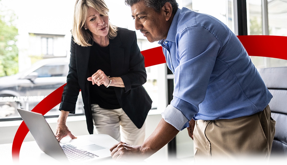 IT admin helping colleague on a laptop in office.