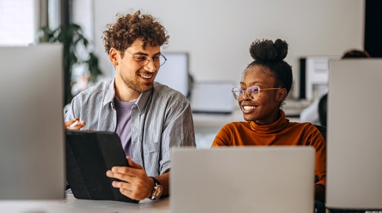 lifestyle image of two coworkers working in an office across multiple devices