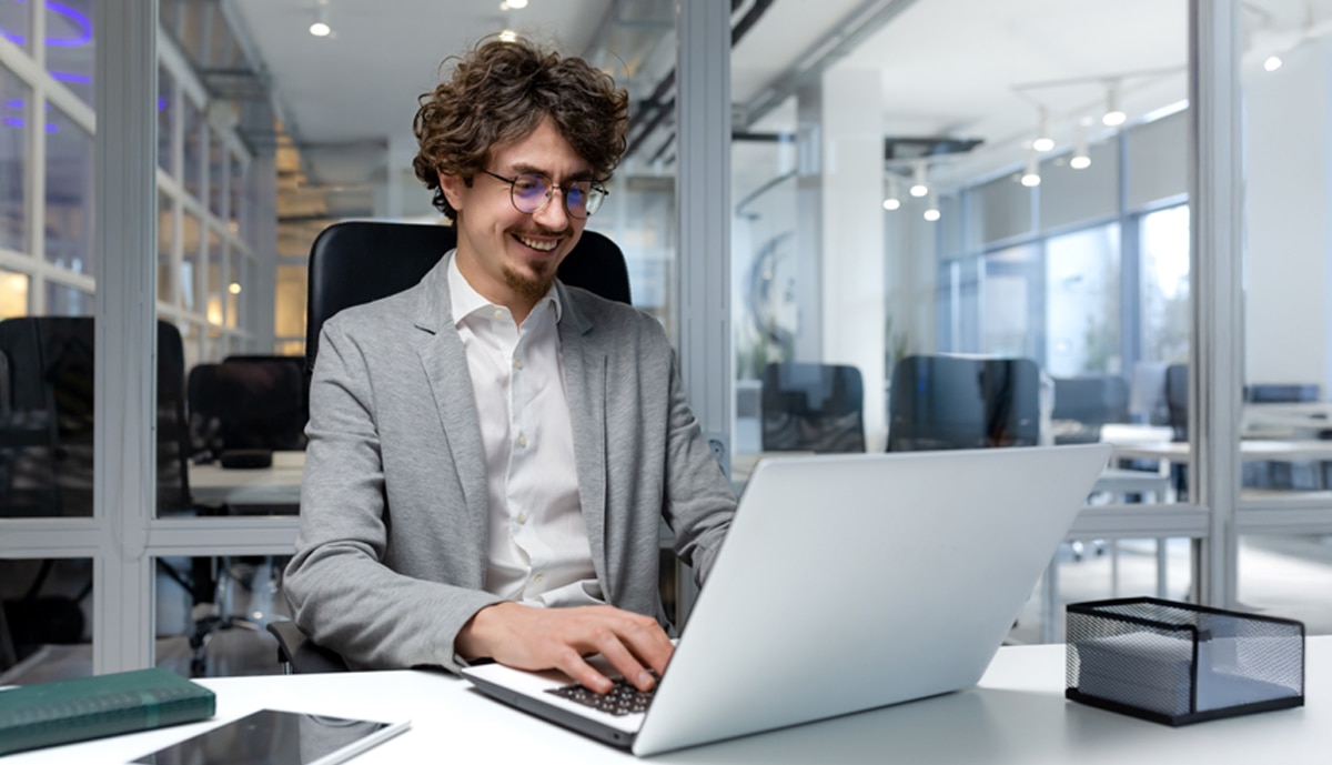 lifestyle image of a man working on a laptop computer in an office environment.