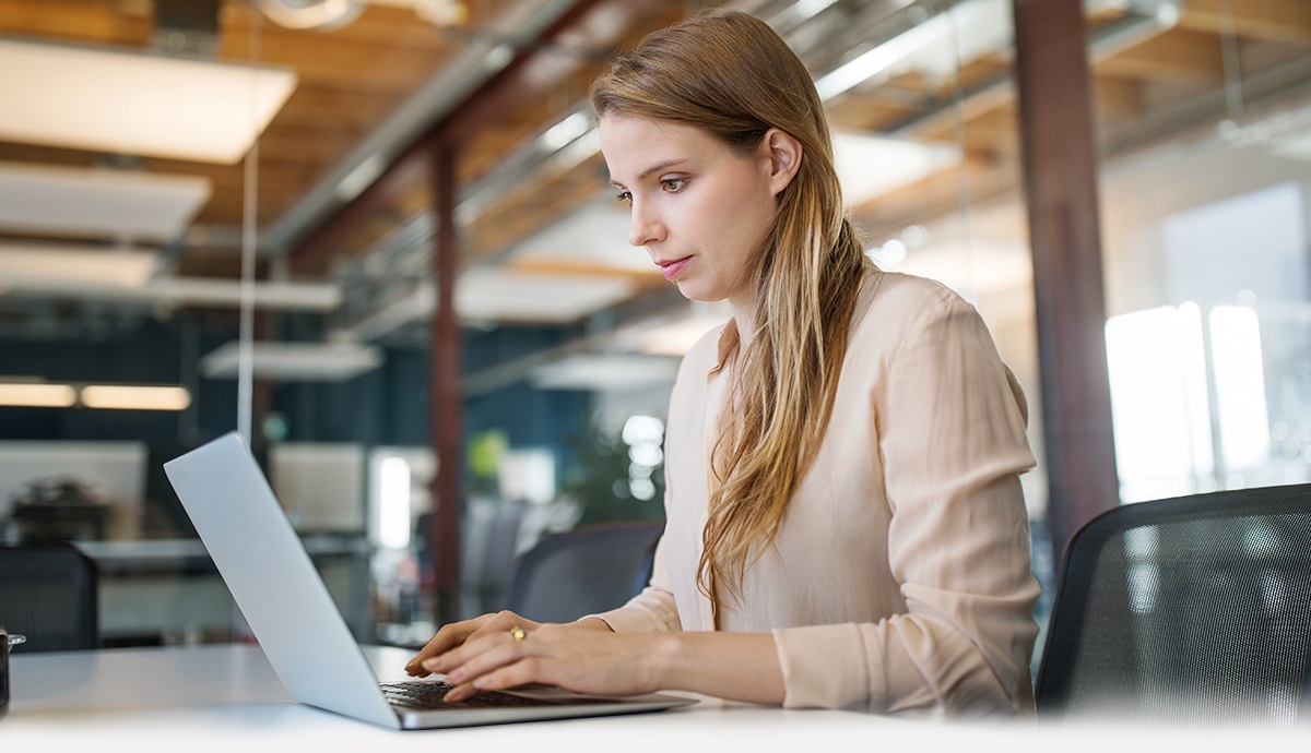 Woman working on a laptop in an office.