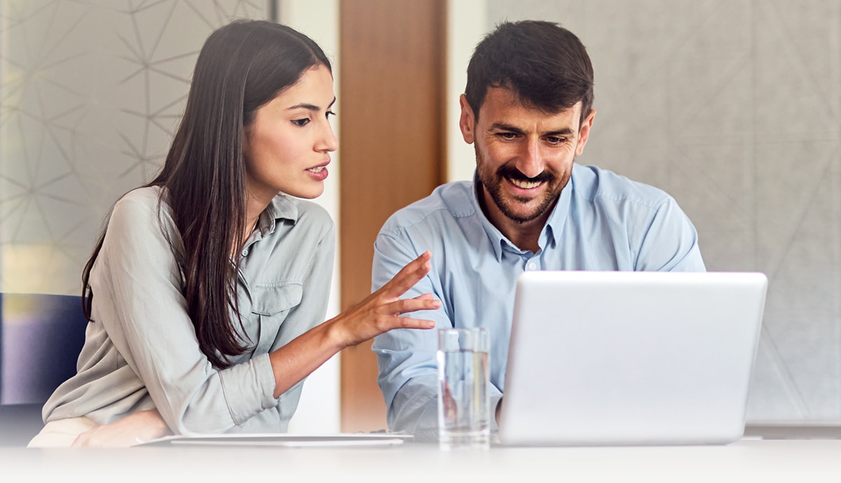 lifestyle image of two coworkers working on a shared laptop.
