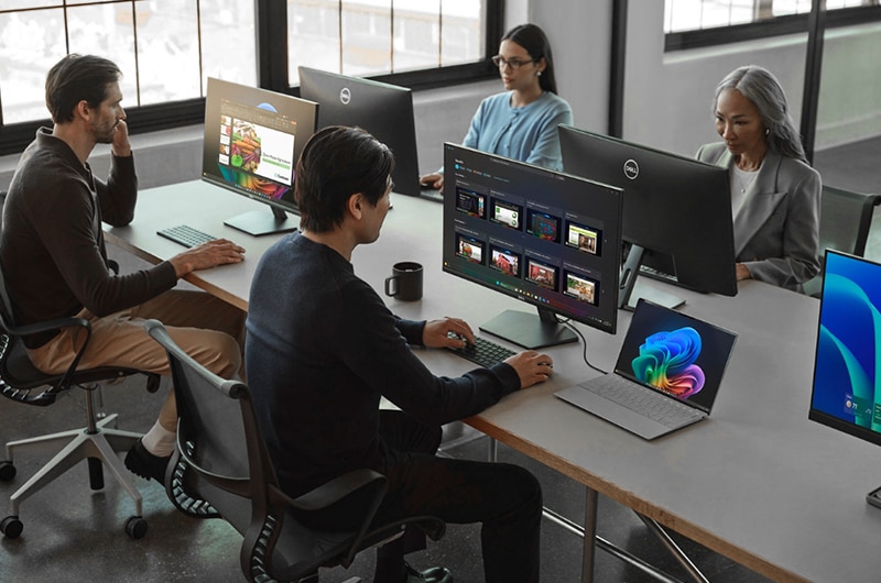 Diverse team collaborating in an office, with a laptop displaying Windows 11.