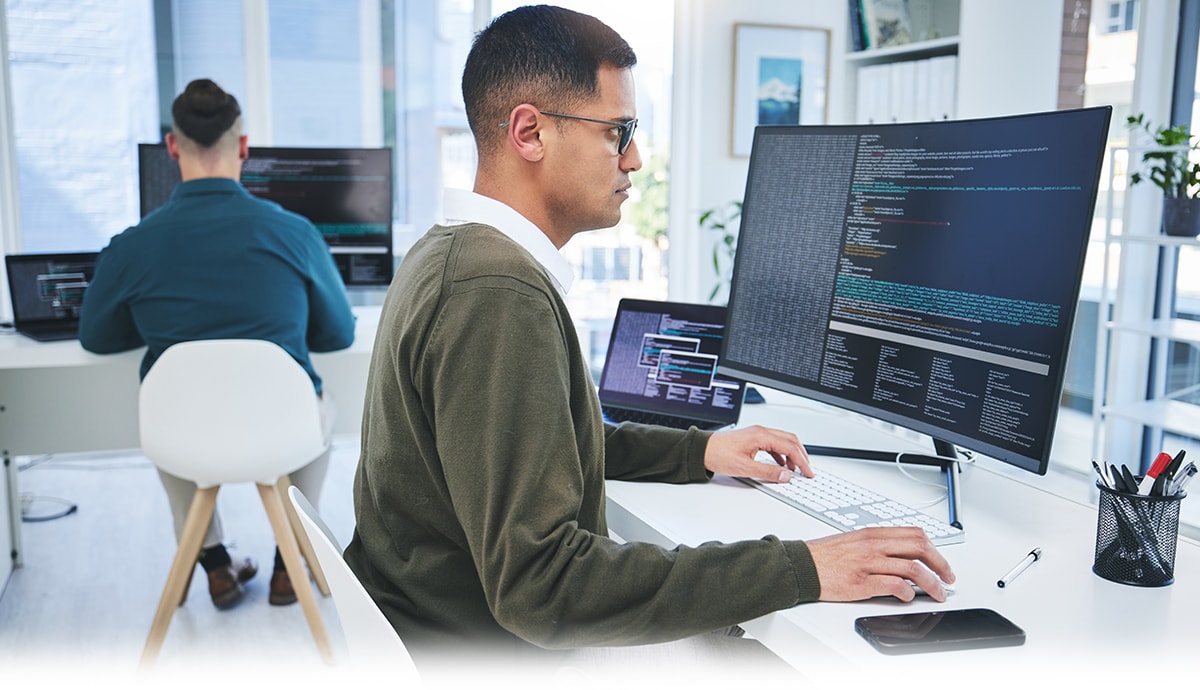 IT specialists coding and managing system operations in a modern office workspace.