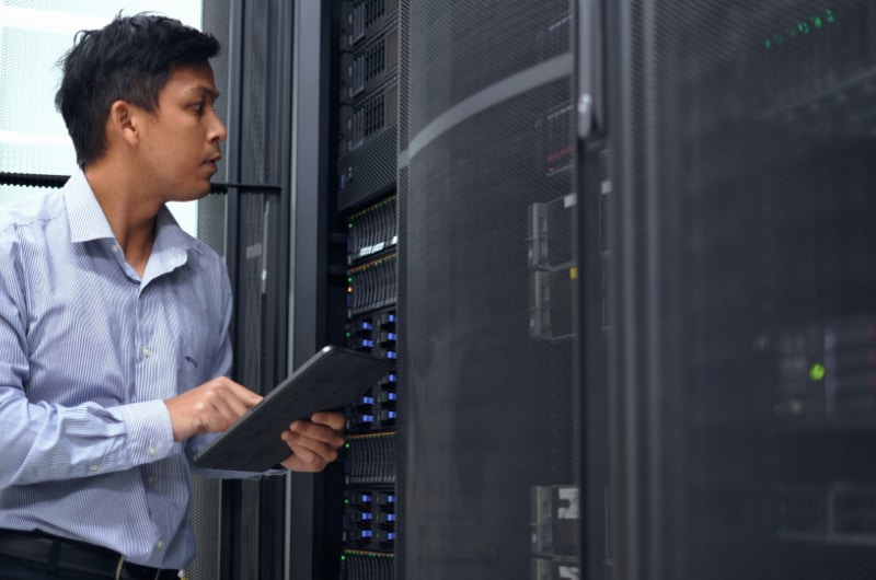 IT Administrator inspecting server racks with a tablet in a secure data center.