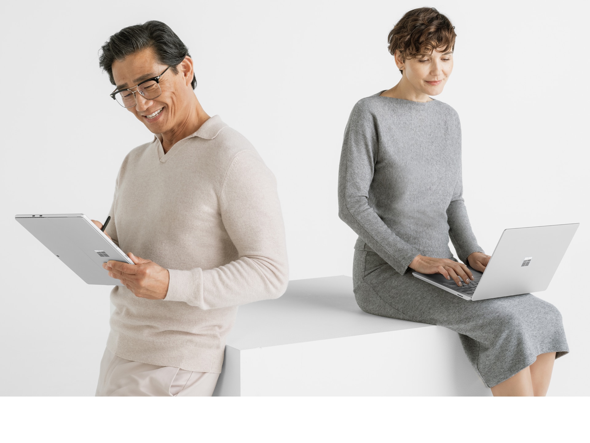 image of a man and woman working on two Microsoft Surface devices.