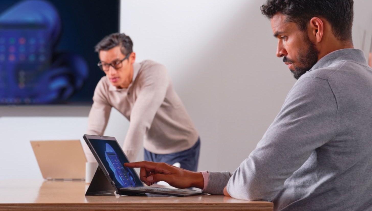 Person interacting with his laptop while sitting in a meeting whilst a meeting is going on.