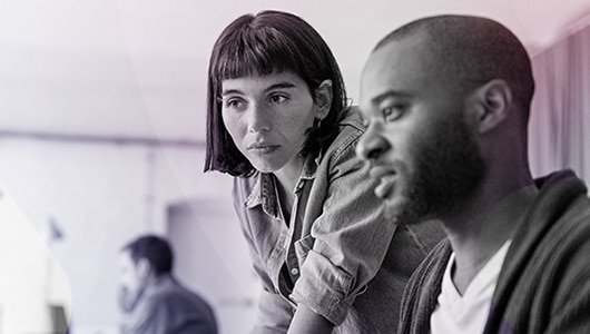 image of two coworkers reviewing information on a computer monitor display