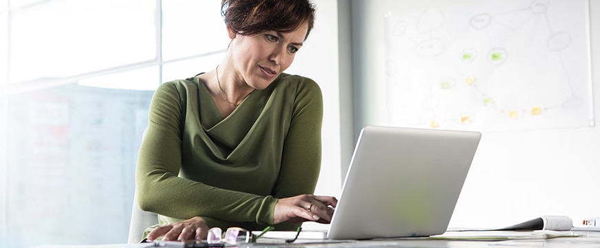 Woman using laptop in bright office.