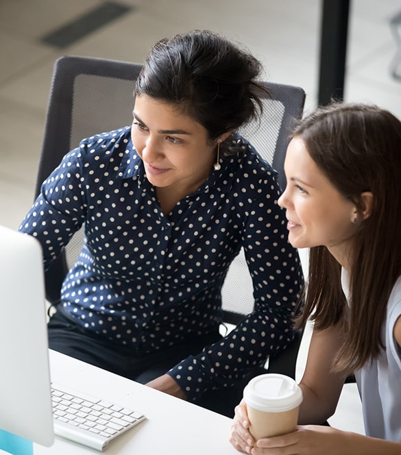 Two woman looking at computer screen.