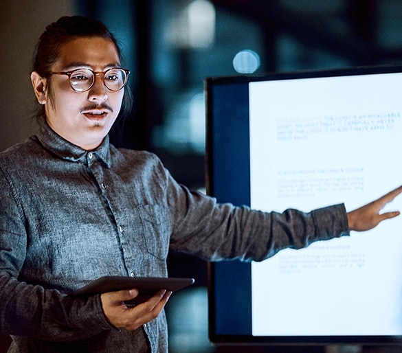 Image of man holding a tablet device and pointing at large display.