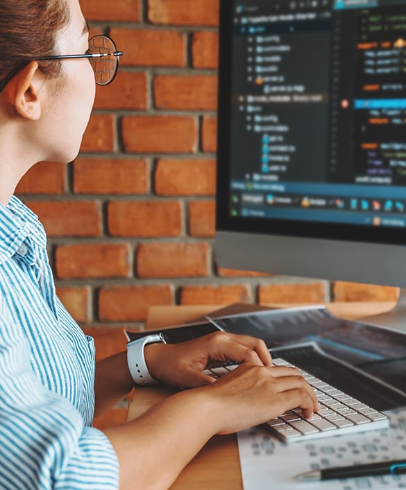 Image of a woman looking at code on a computer screen.