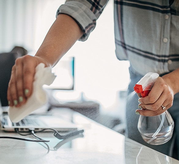 Image of person sanitizing office desk.