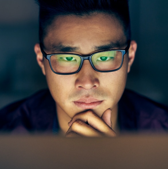 Close up image of a man with glasses reviewing a device screen.