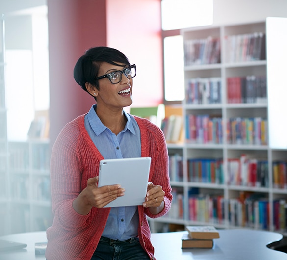 Female teacher in classroom setting using a tablet device.