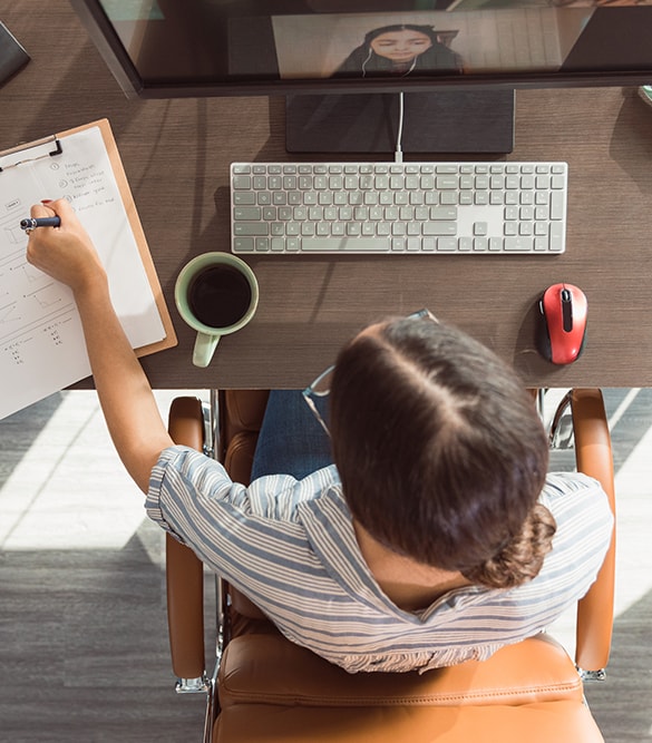 Top down view of teacher at desk attending a video conference.