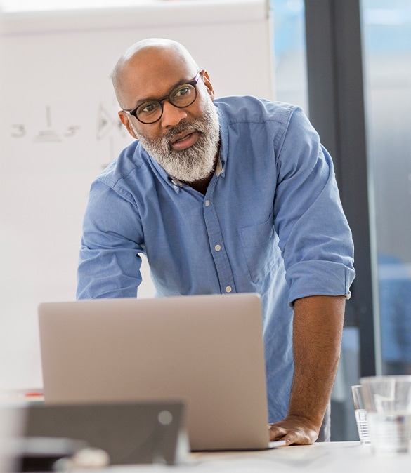 Male teacher standing at table with laptop.