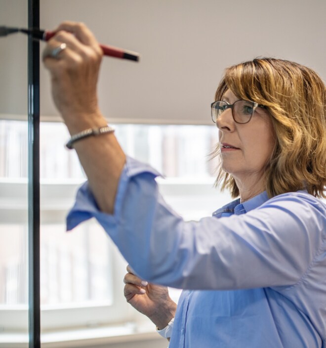 Close up image of a woman writing on a white board.