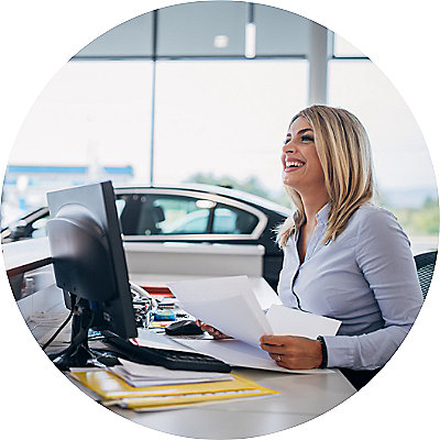 A smiling business woman engaged in a conversation at a dealership.