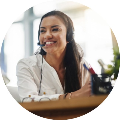 A young woman smiling and having a conversation in an office using a headset.