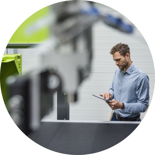 Man using tablet device on factory floor.