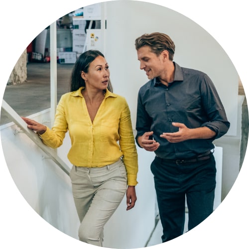 Two colleagues discussing while walking up the stairs in a modern office.