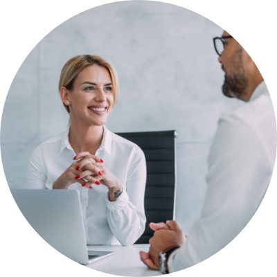 Male and female professionals talking in an office using a laptop.